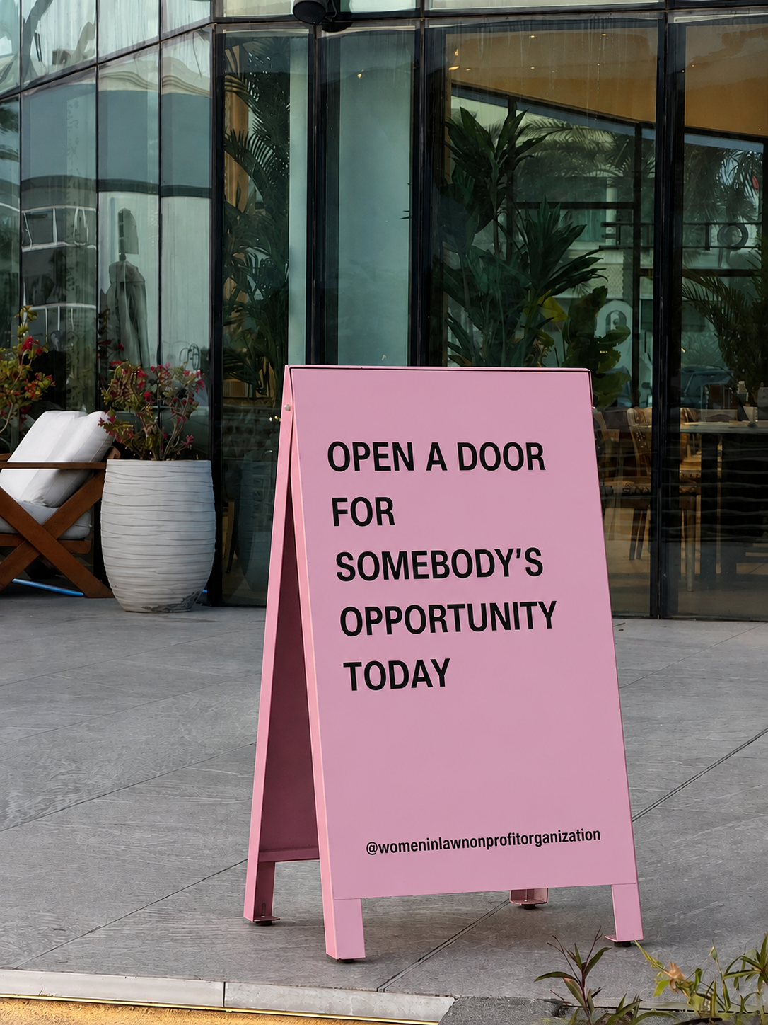 Pink A-frame sign reading: Open a door for somebody's opportunity today